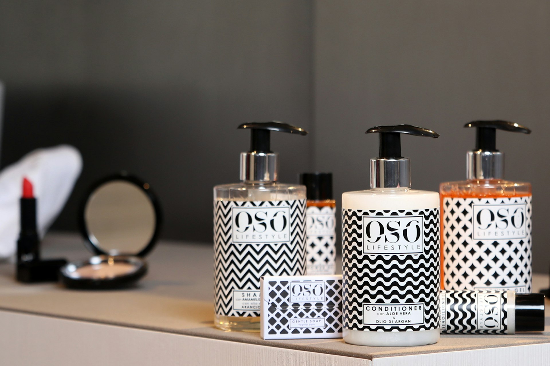 A counter with three bottles of soap and a mirror